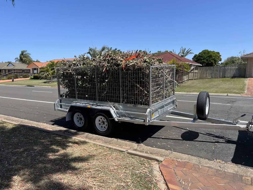 A tandem trailer loaded high with cut branches and garden waste